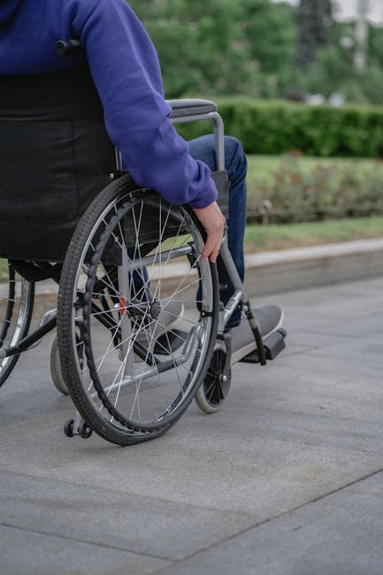 Individual in a wheelchair on a paved walkway outdoors, showcasing mobility and independence.